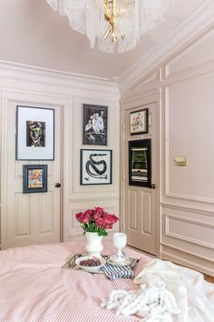 a bedroom with pictures on the wall and a chandelier hanging from the ceiling