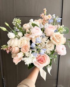 a person holding a bouquet of flowers in their hand with the background painted gray and white