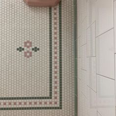 a bathroom with a pink toilet and tiled wall next to a urinal in the corner