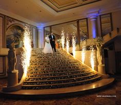 a bride and groom are walking down the stairs at their wedding reception with sparklers coming from them