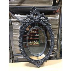 an ornate black mirror sitting on top of a wooden table next to stacks of boxes