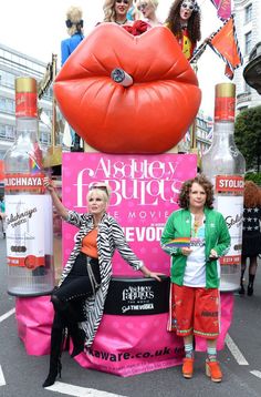 two women are standing in front of a display with giant lips and lipstick on it