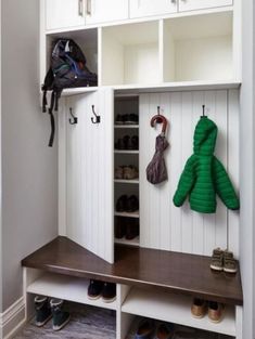 a coat rack with two coats hanging on it and some shoes in the back ground