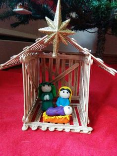 a small christmas ornament with two people in a tiny wooden cage under a tree