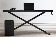 a laptop computer sitting on top of a black table next to a trash can and phone