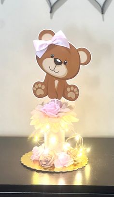 a brown teddy bear sitting on top of a table next to a light up cake