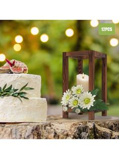 a wedding cake with white flowers and greenery next to a small wooden candle holder