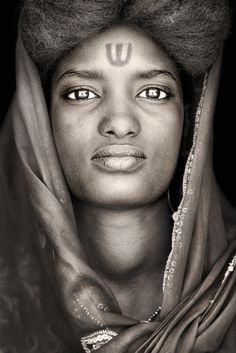 a black and white photo of a woman with the letter u painted on her forehead