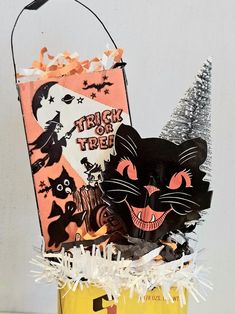 a trick or treat bag with a black cat in it and an orange halloween bag behind it