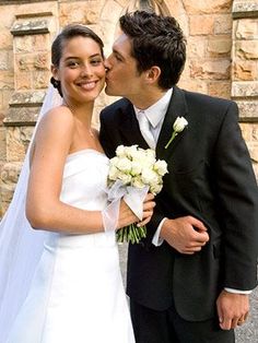 a bride and groom kissing in front of a church