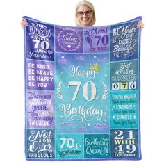 a woman holding up a birthday blanket with the words happy 70th birthday on it