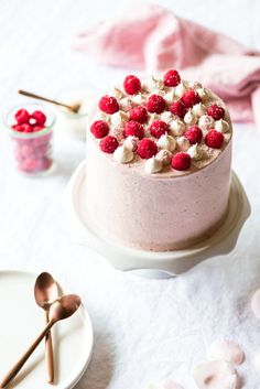 a cake with raspberries and marshmallows is on a white plate