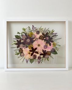 an arrangement of flowers in a white frame