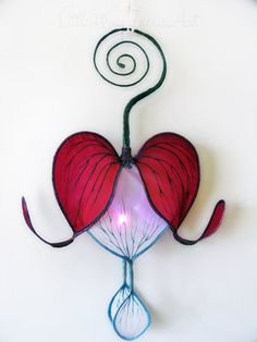 a red heart shaped object hanging from the side of a wall with a spiral design on it