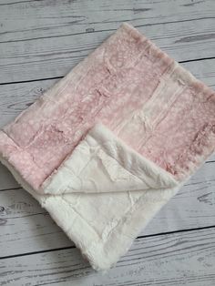 a pink and white blanket laying on top of a wooden floor