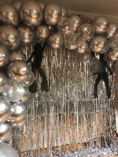 silver balloons and streamers hanging from the ceiling in front of a mirror ball backdrop