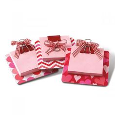 three pink gift bags with bows and hearts on them