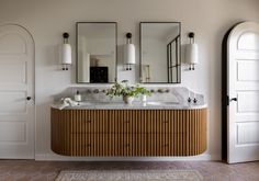 a bathroom with two sinks and three mirrors on the wall next to an arched doorway