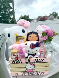 a hello kitty doll sitting on top of a wooden crate filled with stuff and flowers