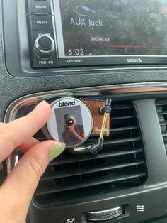 a woman is holding the radio in her hand and pressing buttons on the car stereo