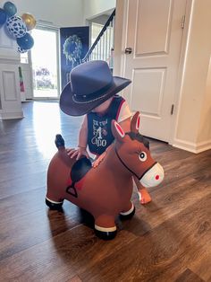 a little boy in a cowboy hat riding a fake horse