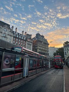 two red double decker buses parked next to each other on the side of a road