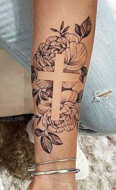 a woman's arm with a cross and flowers on it