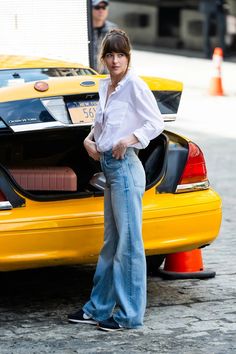 a woman standing next to a yellow taxi