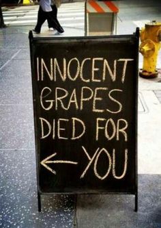 a sign that says innocent grapes died for you next to a yellow fire hydrant