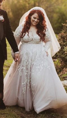 a bride and groom walking through the woods together in their wedding gowns, holding hands