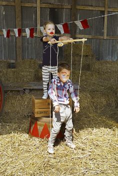 two young children standing on top of hay bales