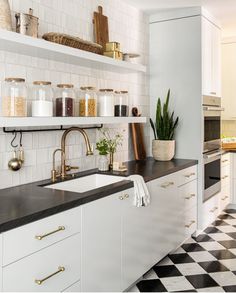 a kitchen with black and white checkered flooring next to shelves filled with jars