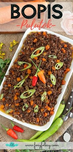 this is an image of a dish with beans and carrots on it, next to some flowers