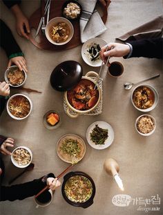 several people are sitting at a table with bowls of food and chopsticks in their hands