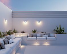 a living room filled with white couches and potted plants