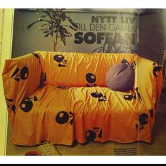 an orange couch with black and white designs on the cover is in front of a poster