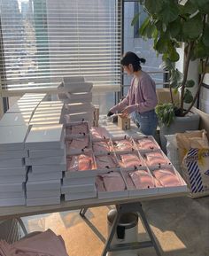 a woman standing in front of a table filled with boxes