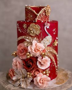 a red and gold wedding cake decorated with flowers