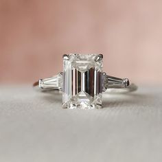 an emerald - cut diamond ring with three baguettes on each side and tapered shoulders