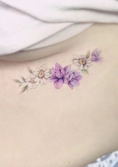 a woman's lower back tattoo with purple flowers