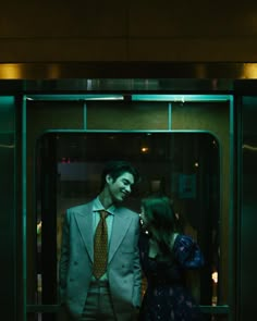 a man in a suit and tie standing next to a woman