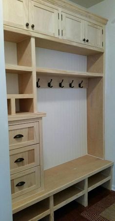 a large wooden shelf with drawers and hooks on it's sides next to a wall mounted coat rack