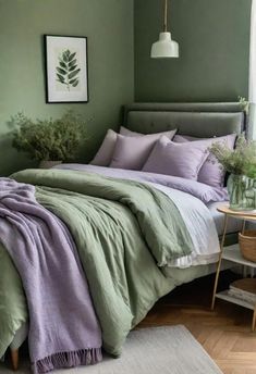 a bed with green and purple sheets in a bedroom next to a table with flowers on it