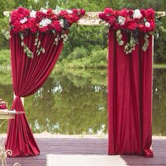 an outdoor wedding setup with red drapes and flowers