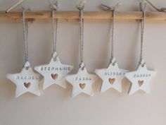 five ceramic stars hanging on a wall with names and hearts attached to the strings that hang from them