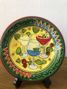 a colorful plate with two drinks on it sitting on a wooden table next to a white wall