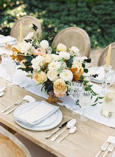 the table is set with white and yellow flowers in vases, silverware, and napkins