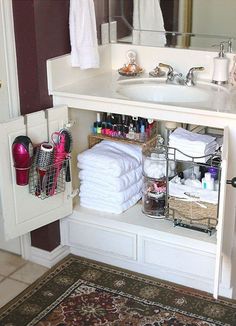 the bathroom cabinet is organized with towels and other things to keep in it's place