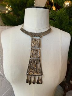 "Spectacular Egyptian Revival 70s/80s necklace. This necklace is the epitome of a statement piece. It is large, detailed, and fabulous!! This necklace has 3 increasing larger flat pieces that have similar designs, attached by rings, so that they have movement. 5 tear drop fringe-type pieces hang at the bottom, making this beauty even more fantastic! *The chain may not be original as it is a slightly different metal, but then again it may be original! Condition: Great condition, with minimal wear Label: none Fabric Content: not marked, but is a heavier metal Size on Label: n/a Measurements: The 3 piece pendant measures 6\" including the tear drop fringes  The chain is short, so it fits close to the neck, measuring approx. 5.5\" long *IMPORTANT NOTE: All measurements are taken with the garme Retro Metal Jewelry For Festival, Retro Festival Metal Jewelry, Retro Metal Necklaces For Festivals, Heavy Metal Necklaces For Parties, Retro Gold Necklace For Festival, Bronze Bohemian Necklace For Party, Bohemian Bronze Necklaces For Party, Bohemian Bronze Necklace For Parties, Heavy Vintage Choker Necklaces