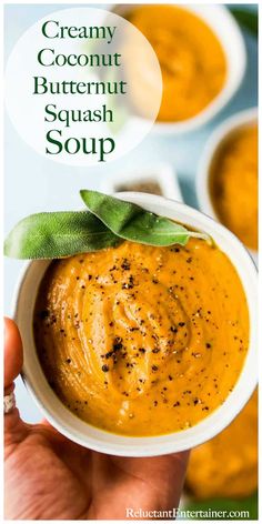 a hand holding a small white bowl filled with creamy butternut squash soup